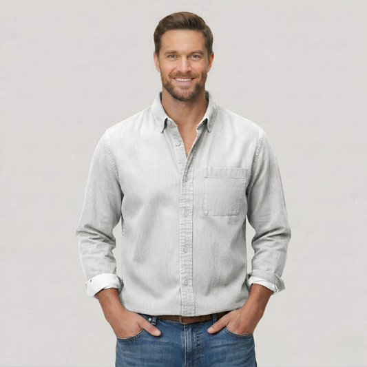 Man wearing a light gray shirt and blue jeans against a plain background